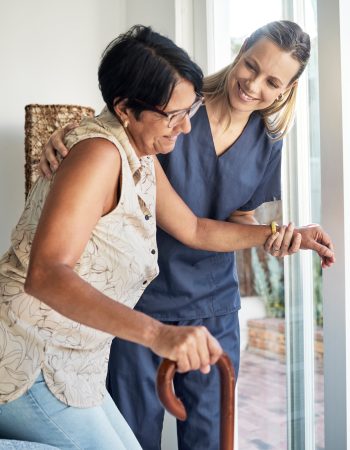 Happy woman, nurse and senior in elderly care, support or walking with stick at old age home. Medical caregiver or therapist helping patient or person with a disability in retirement or physiotherapy.